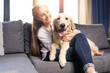 teenager girl hugging golden retriever dog on sofa at home