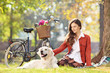 Beautiful female sitting on a grass with her dog in a park